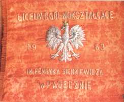 Na zdjęciu widać sztandar szkoły. Na środku znajduje się Godło Narodowe. Nad godłem widać wyszyty napis Liceum Ogólnokształcące a pod godłem wyszyty napis imienia Hernyka Sienkiewicza w Pajęcznie.
Godło umieszczone jest między datą ufundowania sztandaru 1963.